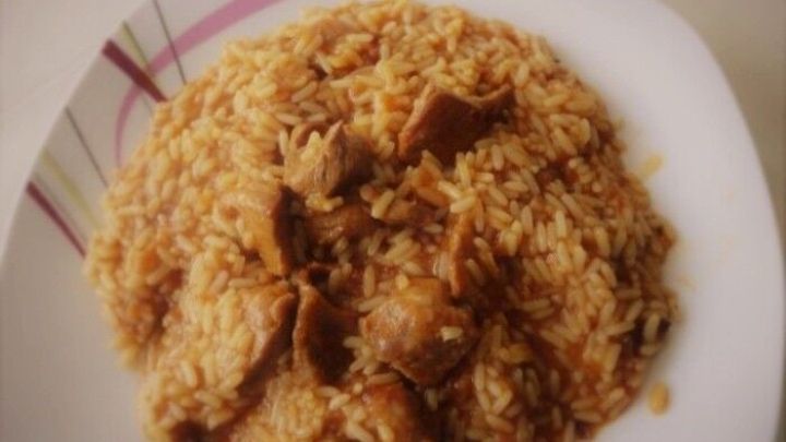 Ein Teller mit Reisfleisch zeigt zartes Fleisch und duftenden Reis, serviert auf einem wei&szlig;en Teller in einer K&uuml;che.