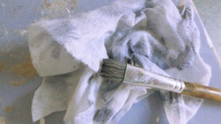 Ein &Ouml;lpflegetuch liegt zusammen mit einem Pinsel auf einem leicht verschmutzten Tisch, bereit f&uuml;r den Einsatz im Haushalt.