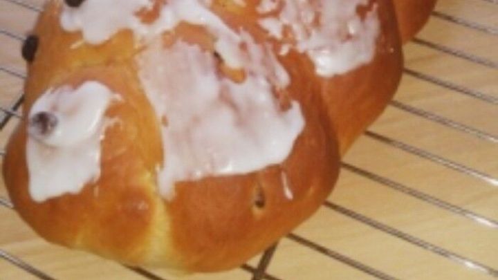 Ein saftiger Hefezopf aus Dinkelmehl liegt auf einem Kuchengitter, frisch gebacken und leicht glasuriert.