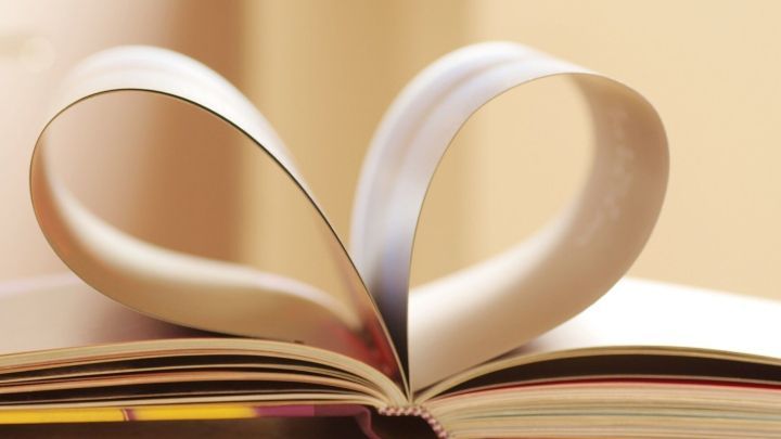 Ein aufgeschlagenes Buch hat Seiten, die sich in Herzform winden, was die Bedeutung des Lesens und Bildung symbolisiert.