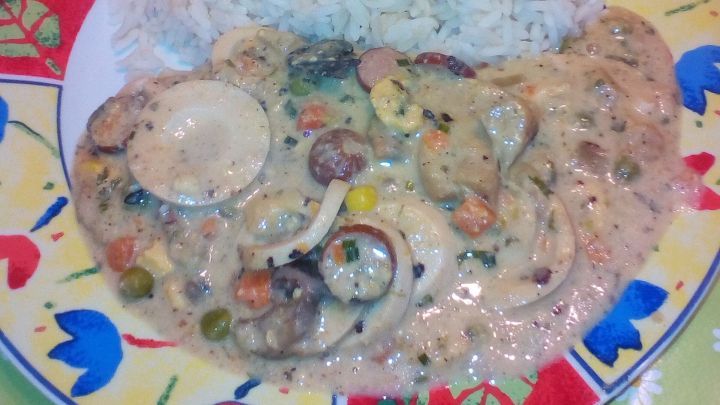 Ein Teller mit Eierfrikassee, umgeben von Gem&uuml;se, liegt neben einer Portion Reis auf einem bunten Teller.