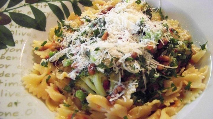 Farfalle mit Brokkoli werden auf einem Teller serviert, garniert mit Parmesan, umgeben von einer dekorativen Randgrafik.