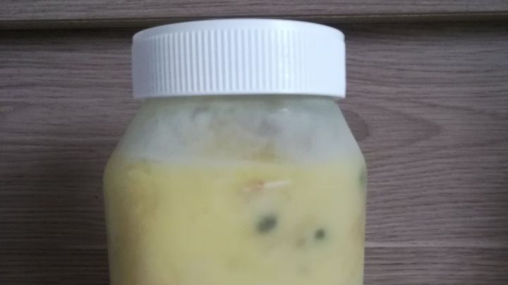 Ein Glas mit gefrorenem Inhalt steht auf einer Arbeitsplatte in einer K&uuml;che. Es zeigt, wie Lebensmittel zum Einfrieren vorbereitet sind.