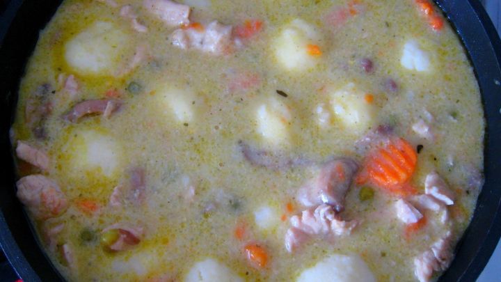 In einer Pfanne k&ouml;chelt Putengeschnetzeltes mit Kartoffelkl&ouml;&szlig;chen in einer cremigen, bunten So&szlig;e.