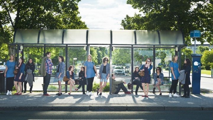 Menschen an einer Haltestelle machen Gymnastik, w&auml;hrend sie auf den Bus warten, um die Wartezeit aktiv zu nutzen.