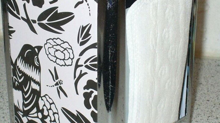 Ein eleganter Beh&auml;lter mit floralem Design bewahrt Slipeinlagen dezent auf und steht auf einer glatten Oberfl&auml;che.