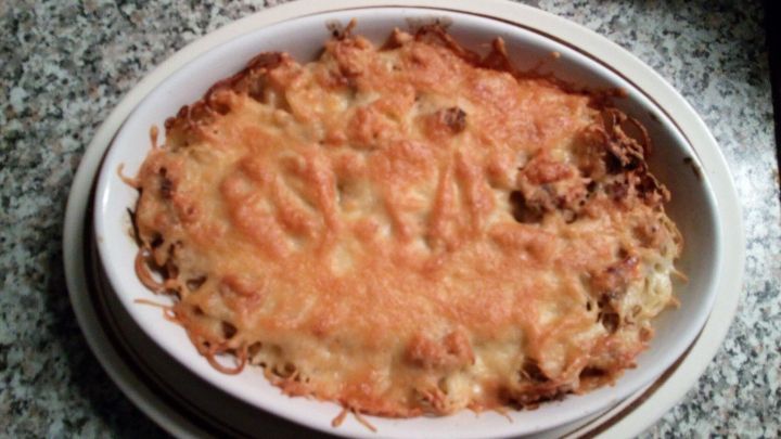 &Uuml;berbackene Thunfisch-Spaghetti sind in einer gebackenem Form zu sehen, knusprig und goldbraun, auf einer marmorierten Oberfl&auml;che.
