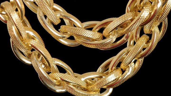 Goldketten liegen &uuml;bereinander und gl&auml;nzen auf schwarzem Hintergrund, ideal f&uuml;r die Reinigung von Schmuck.