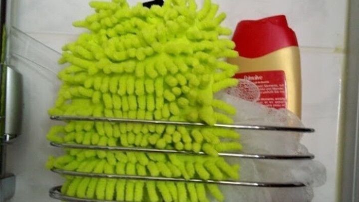 Ein flauschiger Putzhandschuh h&auml;ngt in einer Duschablage, neben einer Flasche Duschgel, bereit f&uuml;r die Reinigung der empfindlichen Haut.