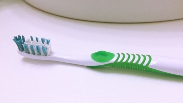Eine Zahnb&uuml;rste liegt auf einem hellen Untergrund, bereit zum Reinigen der Fingern&auml;gel. Sie hat eine gr&uuml;ne und wei&szlig;e Farbgestaltung.