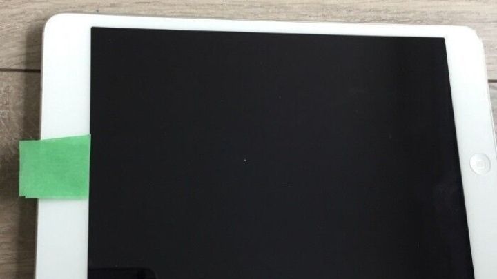 Ein Tablet liegt auf einem Holztisch, es hat ein gr&uuml;nes Klebeband auf der oberen Kante zum Schutz vor Kamera-&Uuml;berwachung.