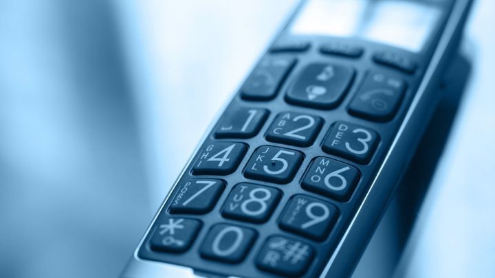 Ein Telefon mit Tasten liegt auf einem Tisch, w&auml;hrend es zum W&auml;hlen bereit ist, im Kontext einer ruhigen Umgebung.