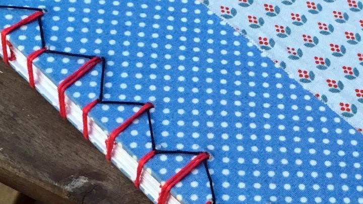 Ein Notizheft mit japanischer Bindung liegt auf einem Holztisch, dekoriert mit hellblauen und gemusterten Seiten.