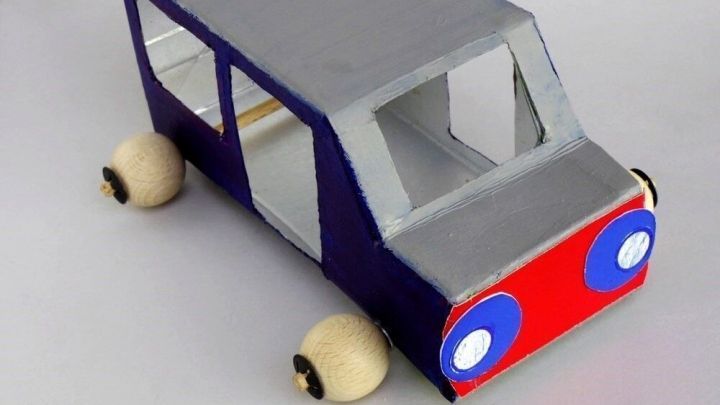 Ein bunter Bus aus Milchkarton steht auf einer Fl&auml;che und zeigt kreative Gestaltung mit Fenstern und R&auml;dern.