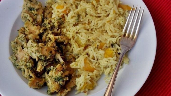 Ein Teller Paprikareis liegt auf einem roten Tisch, umgeben von einem silbernen Besteck und einem vegetarischen Hauptgericht.