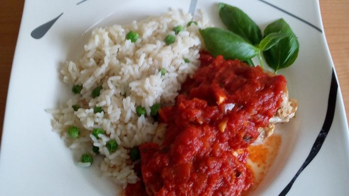 H&auml;hnchenbrust wird mit gehackten Tomaten serviert, begleitet von gr&uuml;nem Reis und frischem Basilikum auf einem wei&szlig;en Teller.