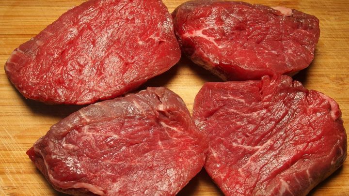 Rohes Fleisch liegt auf einem Holzbrett, was auf eine m&ouml;gliche Zubereitung in einer K&uuml;che hinweist, wo frische Lebensmittel wichtig sind.