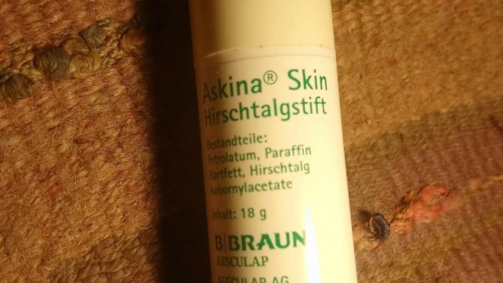 Ein Hautschutzstift liegt auf einer gestreiften, wollenen Decke. Er dient zur Behandlung einer roten Schnupfennase.