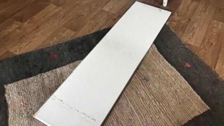 Eine wei&szlig;e Fl&auml;che liegt auf einem Teppich, w&auml;hrend sie von einem Schrank und einer Kommode umgeben ist.