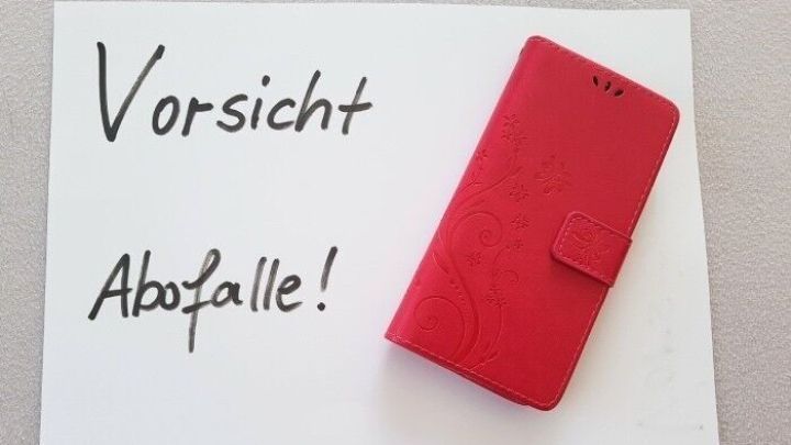 Ein rotes Smartphone-Cover liegt neben einer Warnung vor Abofallen auf einem wei&szlig;en Blatt, das zur Vorsicht mahnt.