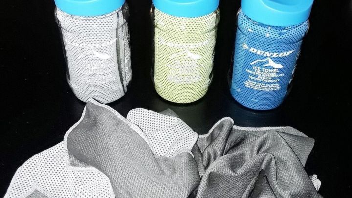 Ein Eishandtuch liegt neben drei farbigen Flaschen und h&auml;lt Lebensmittel im Sommer k&uuml;hl und frisch.