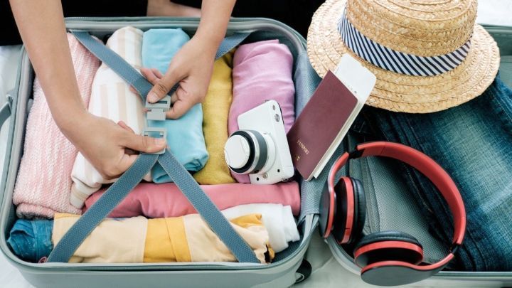 Ein Koffer wird sorgf&auml;ltig platzsparend gepackt, w&auml;hrend Kleidung und Accessoires ordentlich angeordnet sind.