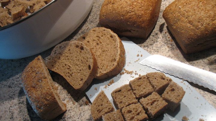 Eine frisch geschnittene Brotsorte liegt auf einem Schneidebrett, w&auml;hrend es St&uuml;cke f&uuml;r die Milchkaltschale dient.