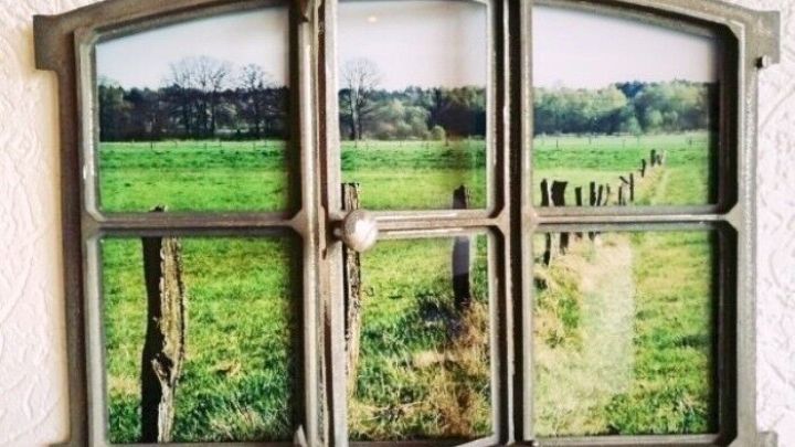Ein aufgeschlagenes Fenster zeigt eine gr&uuml;ne Wiese und einen Zaun, das Wandbild vermittelt eine nat&uuml;rliche, l&auml;ndliche Atmosph&auml;re.