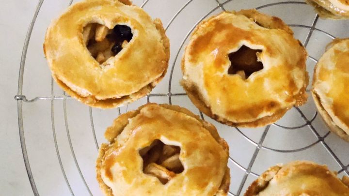 Gedeckte Bratapfel-Muffins liegen frisch auf einem Kuchengitter und warten auf den Verzehr, verziert mit Herz- und Sternformen.