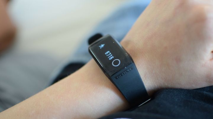 Ein Fitnessarmband liegt auf einem Handgelenk und zeigt Aktivit&auml;tsdaten, w&auml;hrend sich eine Person entspannt.