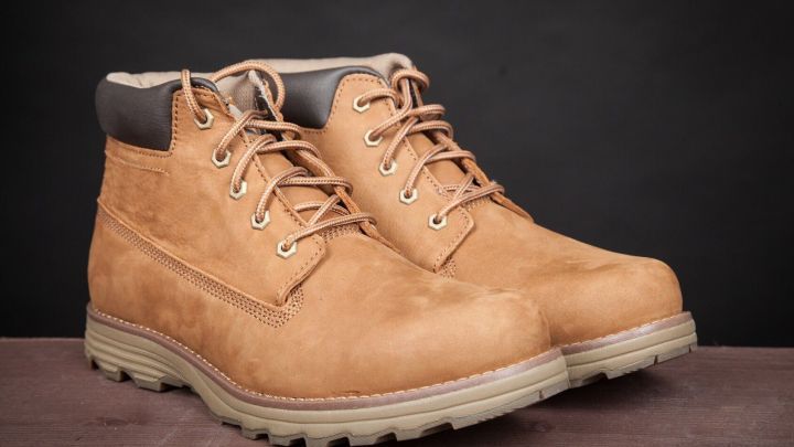 Braune Schuhe stehen auf einer Oberfl&auml;che, bereit, Schneer&auml;nder entfernt zu werden, im neutralen Hintergrund.