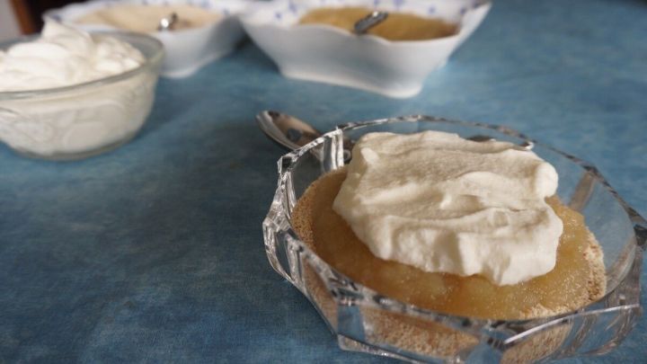 Eine d&auml;nische Torte wird serviert, garniert mit Sahne, auf einem blauen Tisch, daneben sind weitere Desserts in Schalen.