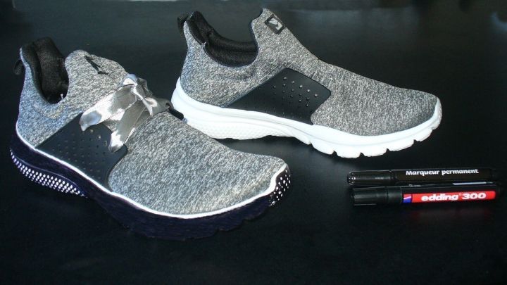 Schwarze Sneakers stehen neben wei&szlig;en Sneakers auf einem Tisch, um m&ouml;gliche Anpassungen der auff&auml;lligen Schuhsohle zu zeigen.