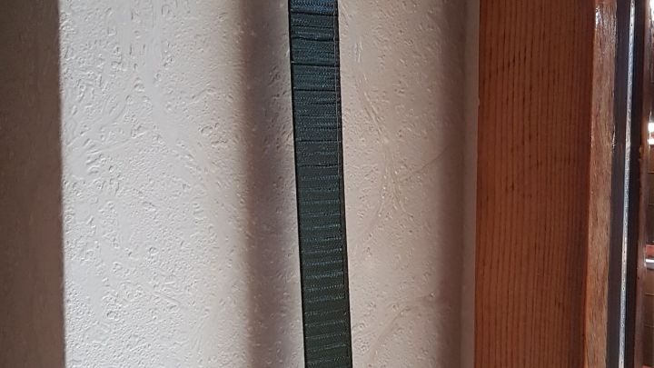 Ein Rollladengurt h&auml;ngt an einer Wand neben einem Fenster und zeigt seine L&auml;nge und Beschaffenheit im Innenraum.