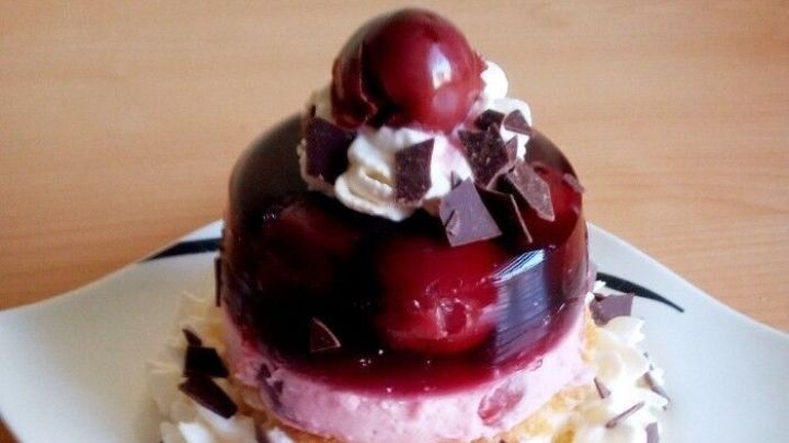 Ein schichtweise aufgebautes Schwarzw&auml;lder-Kirsch-Dessert auf Biskuit, dekoriert mit Sahne, Kirschen und Schokoladensp&auml;nen.