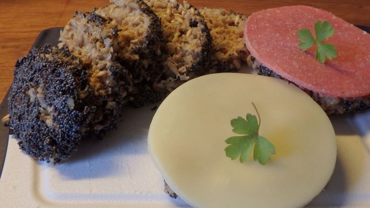 Tassenbrot mit Flohsamenschalen liegt auf einem Teller, umgeben von Scheiben K&auml;se und Wurst, garniert mit Petersilie.