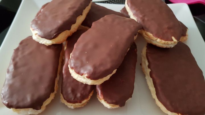 Auf einem wei&szlig;en Teller liegen mehrere Teezungen aus Bl&auml;tterteig, sch&ouml;n mit Schokolade &uuml;berzogen, appetitlich angerichtet.