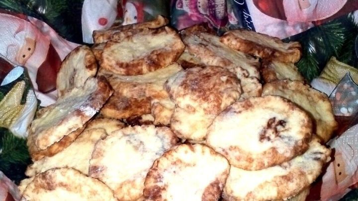 Ein Stapel goldbrauner Pl&auml;tzchen liegt in einer festlichen Schale, umgeben von Weihnachtsdekorationen.