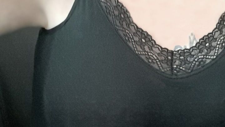 Ein schwarzes Top mit zartem Spitzensaum verdeckt dezent den Achselbereich und die Taille, betont aber die Silhouette.