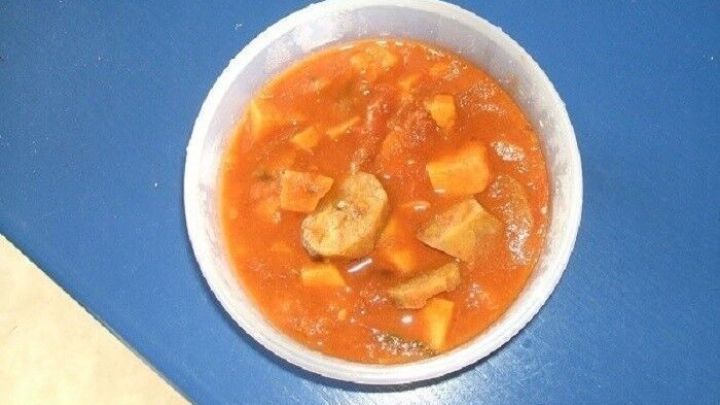 Ein Eintopf nach afrikanischer Art wird in einer wei&szlig;en Sch&uuml;ssel serviert und enth&auml;lt bunte Gem&uuml;sew&uuml;rfel in einer tomatigen Br&uuml;he.