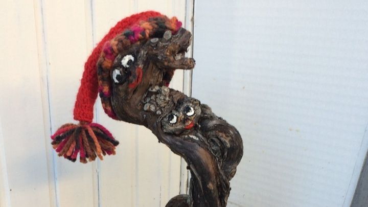 Ein festlich dekorierter Blumentopf mit einem Weihnachtswichtel in rot und Tannenzapfen als Eingangsdeko.