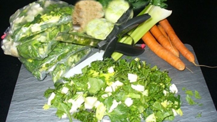 Frisches Gem&uuml;se wird mit Scheren auf einem Schneidebrett zerkleinert, um f&uuml;r herzhafte Suppen oder Eint&ouml;pfe vorbereitet zu werden.