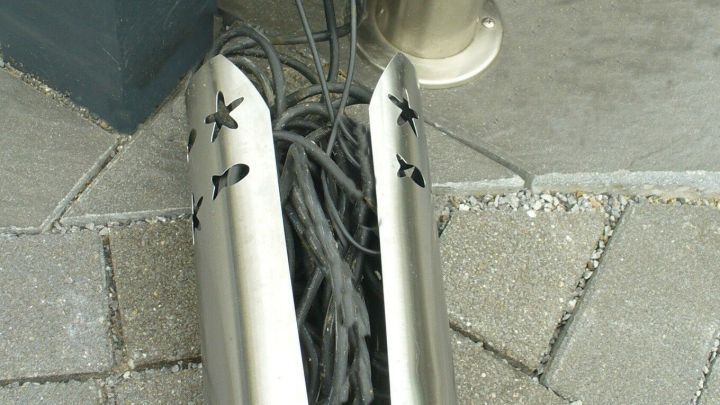 Ein WC-Rollenhalter beherbergt Kabel, die ordentlich verstaut und vor Sicht gesch&uuml;tzt sind, auf einem Boden aus Pflastersteinen.