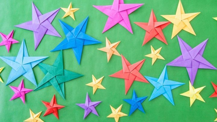 Bunte Sterne aus Geschenkpapier schm&uuml;cken ein gr&uuml;nes Fenster, um eine festliche Atmosph&auml;re w&auml;hrend der Weihnachten zu schaffen.