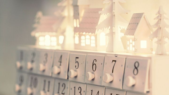 Ein dekorativer Adventskalender mit kleinen H&auml;uschen, der in einer festlichen Umgebung leuchtet und die Tage bis Weihnachten z&auml;hlt.