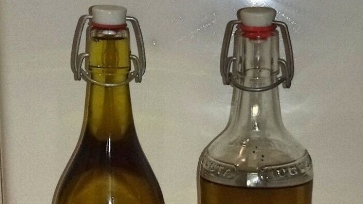 Zwei Flaschen mit hellbraunem Badezusatz f&uuml;r Erk&auml;ltungen und Entspannung stehen auf einer Oberfl&auml;che in einem Bad.