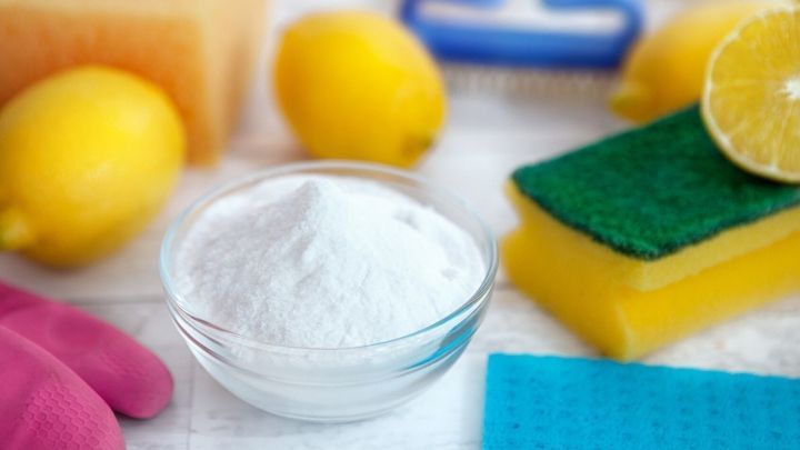 In einer sauberen K&uuml;chenszene befinden sich Zutaten zur Herstellung von selbst gemachtem Putzmittel: Zitronen, Schw&auml;mme und wei&szlig;es Pulver.