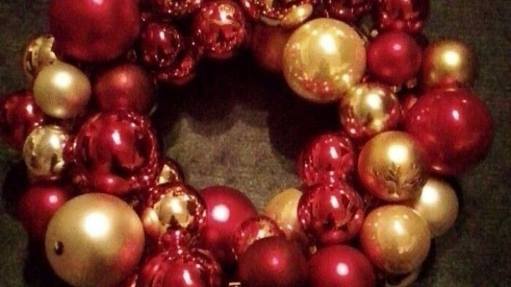 Ein extravagante Weihnachtskranz aus roten und goldenen Kugeln liegt auf einem dunklen Untergrund und strahlt festliche Stimmung aus.