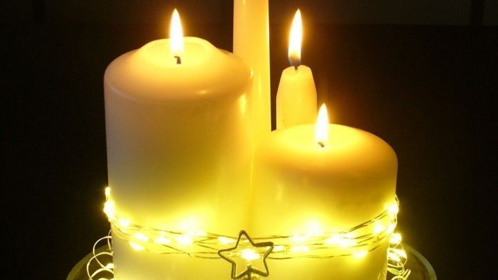 Ein stimmungsvolles Kerzenarrangement erleuchtet den Tisch mit wei&szlig;en Kerzen und strahlenden Lichtern in einem festlichen Dekor.