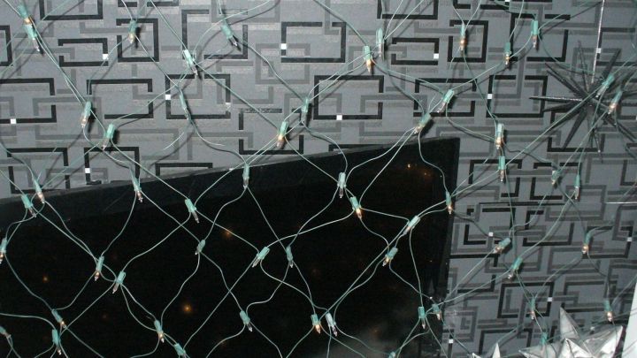 Ein Lichternetz aus Kabeln wird an einer dunklen Wand montiert, wodurch es einen modernen, dekorativen Look schafft.